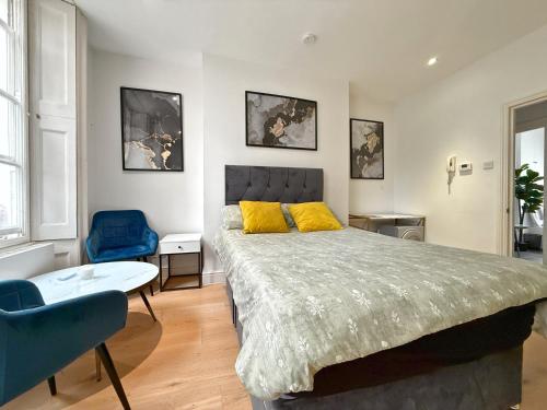 a bedroom with a large bed and a blue chair at Posh Soho Studio Large Windows by Oxford St, Mayfair W1 in London
