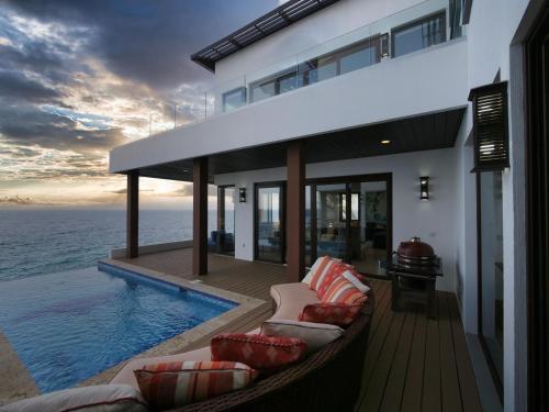 a house on the beach with a hammock and the ocean at Eagle Ray - A Luxurious Waterfront Villa, in Gibson Bight