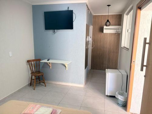 a room with a table and a tv on the wall at Hotel Santo Antonio in Botucatu