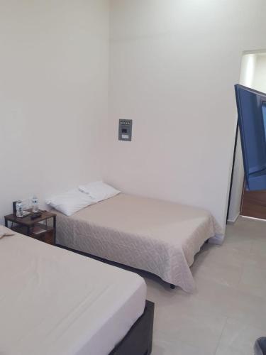 a bedroom with two beds and a night stand with a bedskirts at Casa Herrera in Santa Cruz Huatulco