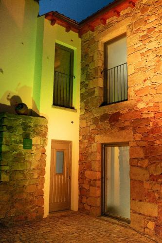a brick building with two windows and a door at Casas do Freixial - Casa do Beco in Fundão