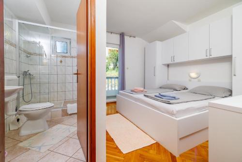 a bathroom with a bed and a shower and a toilet at Apartments Tariba in Supetarska Draga