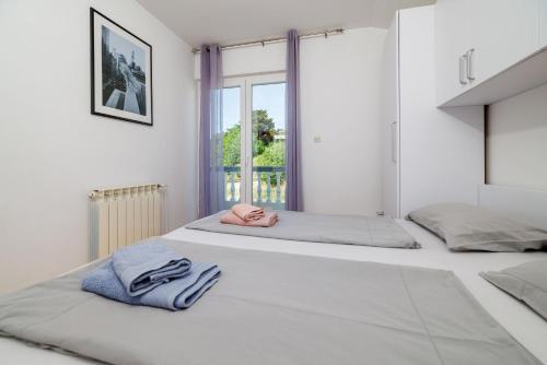 two beds in a white room with towels on them at Apartments Tariba in Supetarska Draga