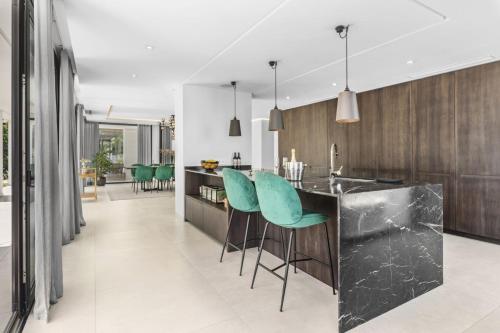 a kitchen with a black counter and green chairs at Sunset Villa With Pool in Bodrum City