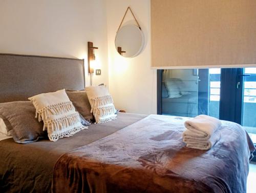 a bedroom with a bed with two pillows and a mirror at Entrañable departamento in Puerto Varas