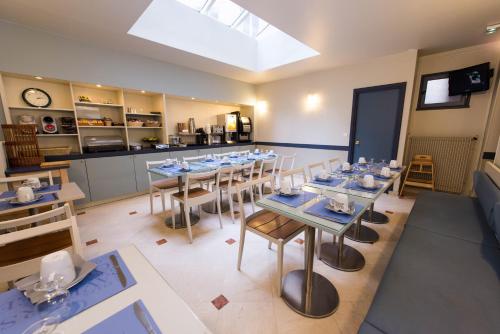una sala da pranzo con tavoli e sedie e una cucina di Kyriad Hotel XIII Italie Gobelins a Parigi