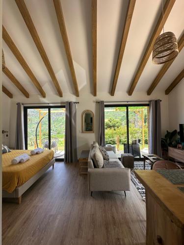 ein Schlafzimmer mit einem Bett und einer Couch und Fenstern in der Unterkunft The Green Valley House II in São Vicente
