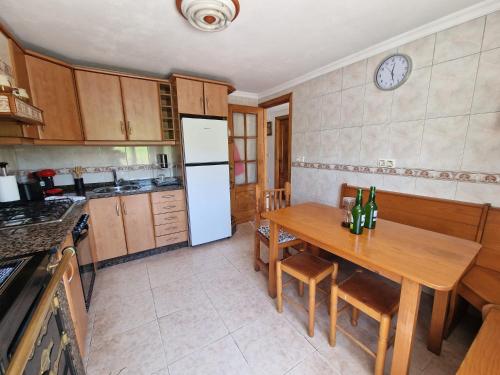 a kitchen with a wooden table and a white refrigerator at Casa de Aldea Quintana in Quintana
