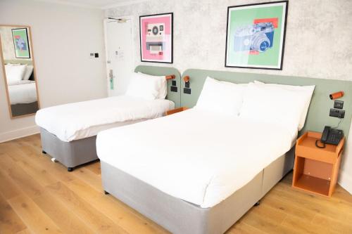 a bedroom with two beds and a mirror at Garner Hotel Reading City Centre, an IHG Hotel in Reading