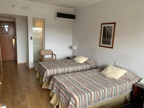 a hotel room with two beds and a chair at Dr Cesar Carman in Cordoba