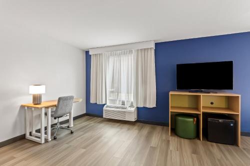 a room with a blue wall and a desk and a television at Spark By Hilton Oak Forest I-57 in Oak Forest