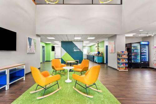 a waiting room with orange chairs and a table at Spark By Hilton Oak Forest I-57 in Oak Forest