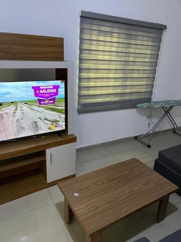 a living room with a flat screen tv and a coffee table at Accra City Apartments 1 in Taifa