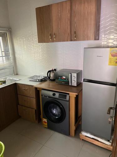 a kitchen with a refrigerator and a washing machine at Accra City Apartments 1 in Taifa