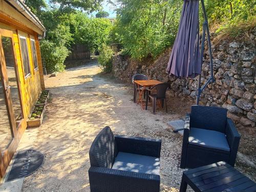 a patio with chairs and an umbrella and a table at Charmant chalet en bois - Ardèche in Joyeuse