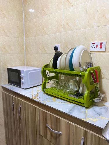 a green rack on a counter with plates and a microwave at Luxury and affordable 2bedroom flat in Lagos, 247light,WiFi in Ijaiye