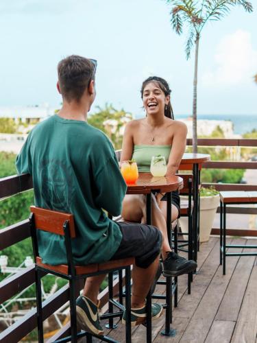 Un hombre y una mujer sentados en una mesa en Maui Hostels Playa del Carmen, en Playa del Carmen