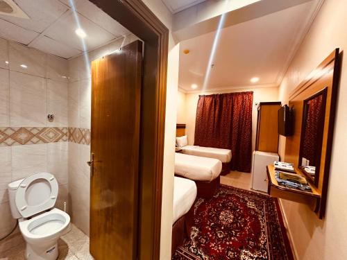 a hotel room with two beds and a toilet at فندق الرسالة رويال in An Naqāʼ