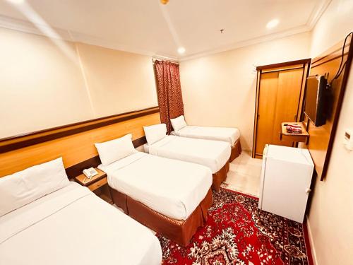 a hotel room with two beds and a tv at فندق الرسالة رويال in An Naqāʼ