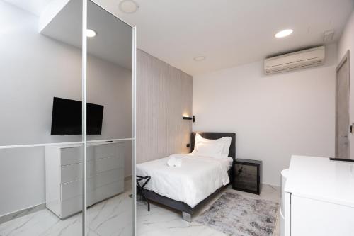 a white bedroom with a bed and a tv at Hotel - Teranea City Hvar in Hvar