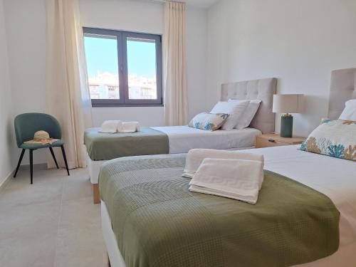 a hotel room with two beds and a window at Edifício da Vinha - Ocean Breeze Apartments in Armação de Pêra