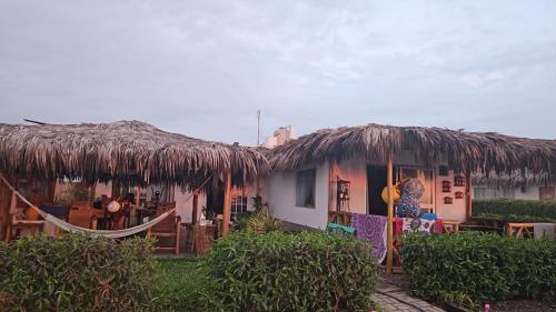 a house with a straw roof and a hammock outside at Beach Rooms Chincha Eco Albergue in Chincha