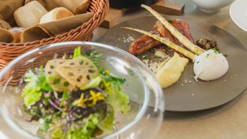 a plate of food with a salad and a basket of bread at 富良野ホテル Furano Hotel in Furano
