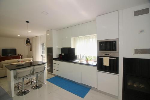 a white kitchen with a sink and a stove top oven at Casa da Idalina in Terras de Bouro