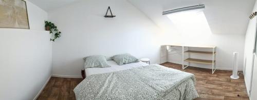 ein weißes Schlafzimmer mit einem Bett und einem Fenster in der Unterkunft Le Ptit Cottage in Landivisiau