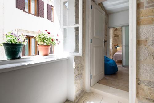 a hallway with a window and two potted plants on a window sill at Apartments Kaja in Trogir
