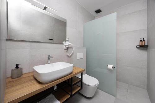 a white bathroom with a sink and a toilet at Hotel - Teranea City Hvar in Hvar