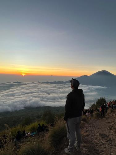 a man standing on top of a mountain looking at the sunset at Volcano Valley in Kintamani