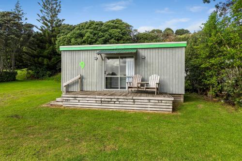 a small shed with two chairs on a lawn at Fitzroy Beach Holiday Park in New Plymouth