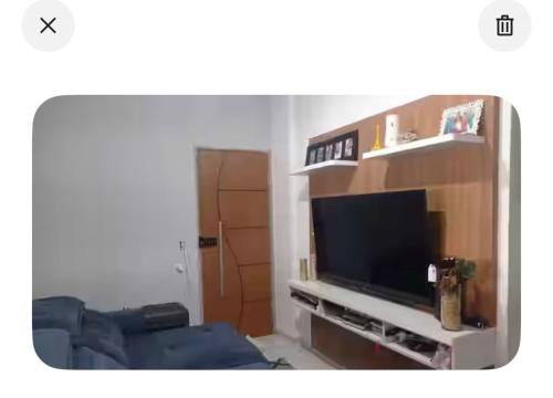 a living room with a flat screen tv on a entertainment center at Apartamento hostel para Mulheres in Vila Velha