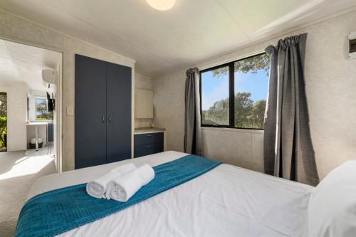 a bedroom with two towels on a bed with a window at Fitzroy Beach Holiday Park in New Plymouth