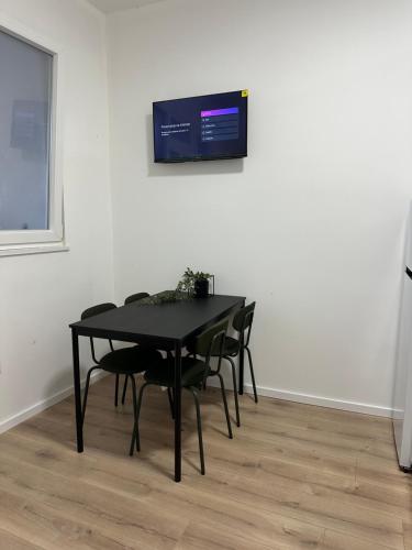 a black table with chairs and a tv on a wall at Apartments Alać in Drasnice