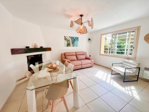 - un salon avec une table en verre et un canapé rose dans l'établissement Les Romarins, à Saint-Tropez