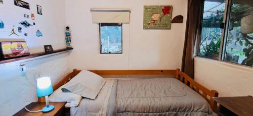 a small bedroom with a bed and a desk with a lamp at Mi Rancho La Paloma in La Aguada