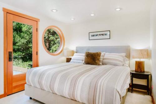 a white bedroom with a bed and a window at Luxe Beachfront, Hot Tub, Kayaking, Walk To Town in Eastsound