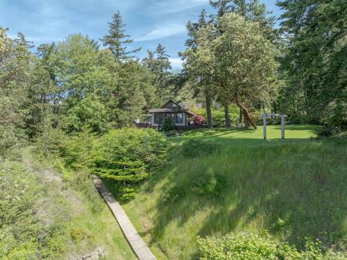 a path through a park with a house in the background at Luxe Beachfront, Hot Tub, Kayaking, Walk To Town in Eastsound