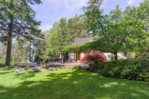 a house with a green yard with a house at Luxe Beachfront, Hot Tub, Kayaking, Walk To Town in Eastsound