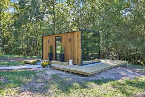 a small wooden cabin with a glass door in a field at Mirror Cabin & Sauna In A Forest in Coldspring