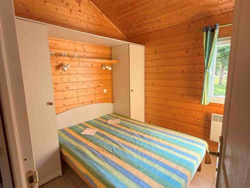 a small bedroom with a bed in a wooden room at Chalet Édelweiss 35 en lisière de forêt, calme et nature - FR-1-583-444 in Mélisey