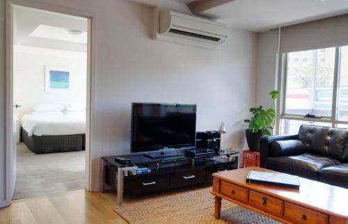 a living room with a couch and a flat screen tv at Fiveways Balcony, King Bed, Chef's Kitchen in Fremantle