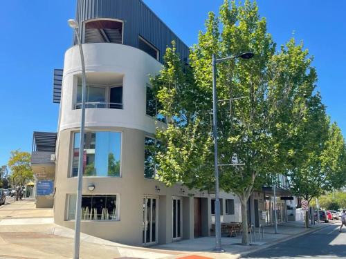 a building with a tree in front of it at Fiveways Balcony, King Bed, Chef's Kitchen in Fremantle