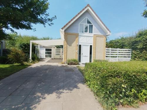 a small house with a white door and a driveway at Cozy Beach House Beautiful Water View, WiFi & Parking in Kamperland