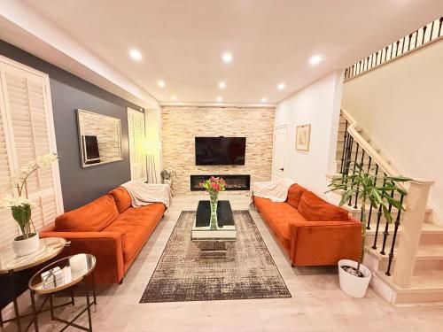 a living room with orange couches and a fireplace at Welcome to Your Home Away From Home! in Mississauga