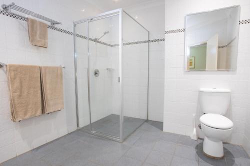 a bathroom with a toilet and a glass shower at Crown Hotel Motel in Camden
