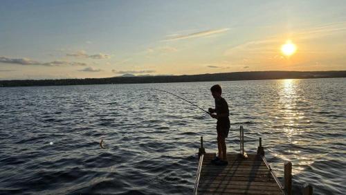 a man fishing on a dock on a lake at La Brise O-Lac in Sherbrooke