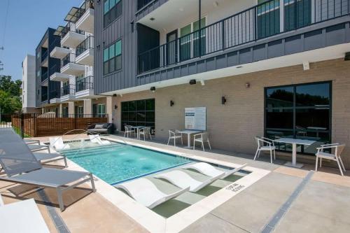 a swimming pool with chairs and a building at Boulevard Stays Comfortable 1BR Suite w Pool Parking Gym 04 in Dallas
